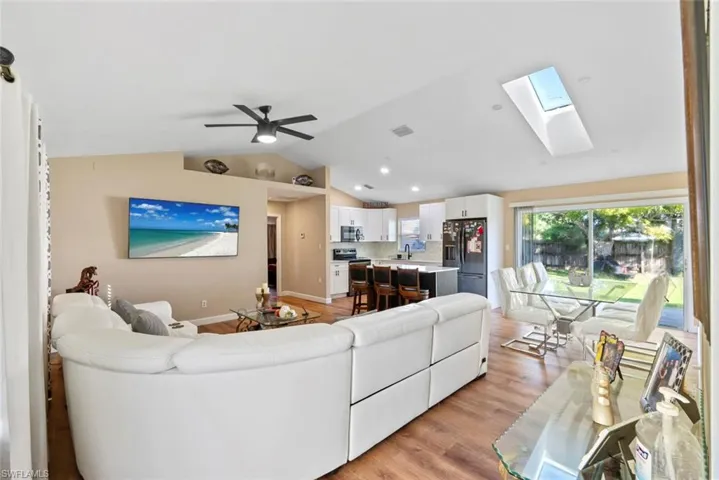 Open-concept living area with wood-finish flooring, vaulted ceiling, and recessed lighting