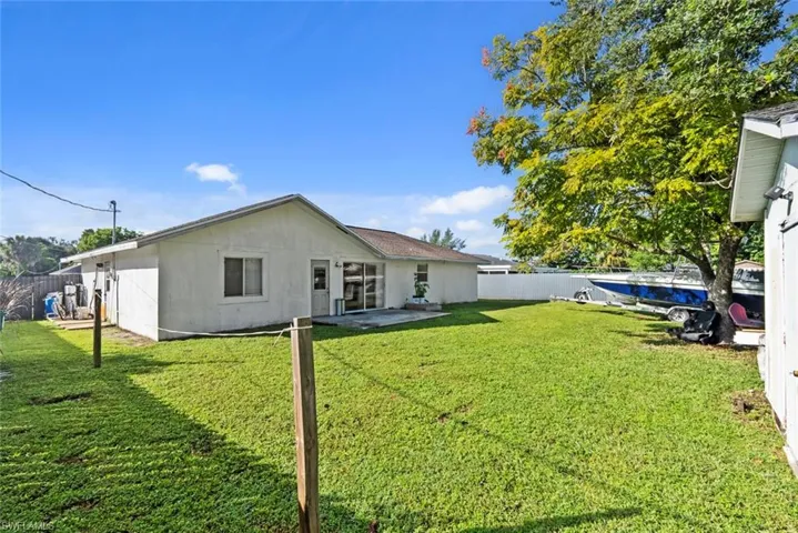 Expansive grassy yard with a white privacy fence and a mature shade tree