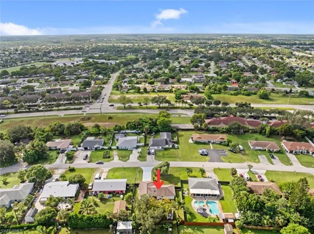 Aerial property overview featuring an in-ground swimming pool, surrounding paved patio, and mature landscaping