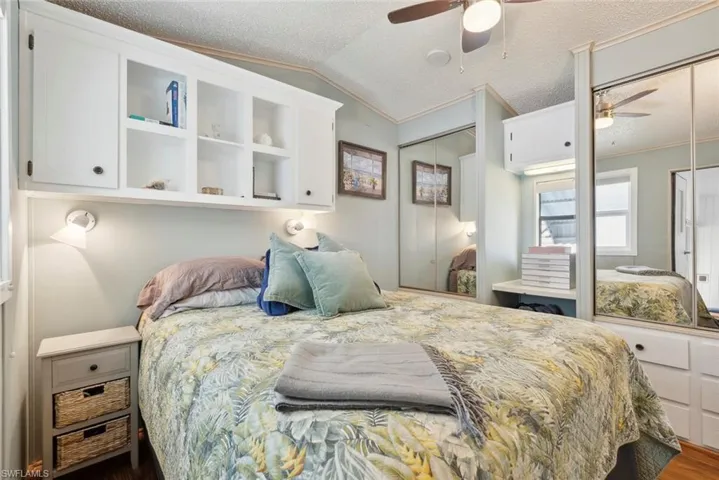 Bedroom with ceiling fan, hardwood / wood-style flooring, a textured ceiling, and lofted ceiling