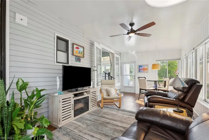 Living room with wooden walls, light wood-type flooring, and ceiling fan