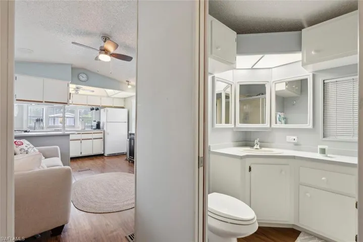 Bathroom with ceiling fan, vanity, lofted ceiling, and hardwood / wood-style floors