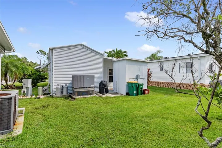 Back of house with central AC unit and a yard