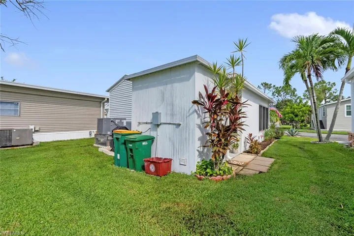 View of side of property featuring cooling unit and a yard