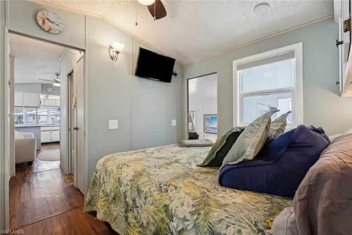 Bedroom featuring ceiling fan, wood-type flooring, a textured ceiling, and multiple windows