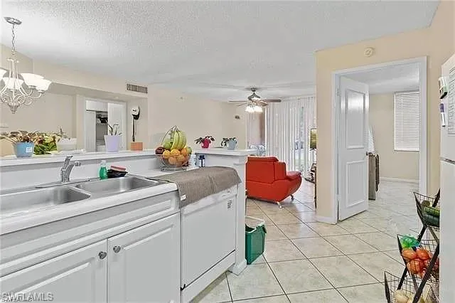 Kitchen featuring white cabinetry, light countertops, a textured ceiling, light tile patterned flooring, and a chandelier