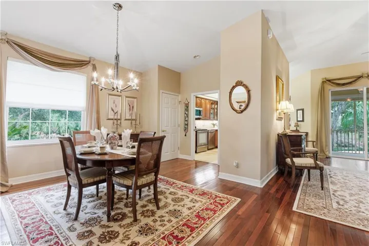 Dining space featuring healthy amount of natural light, dark wood finished floors, and a chandelier