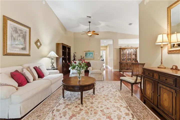 Living room with light wood finished floors, lofted ceiling, and ceiling fan