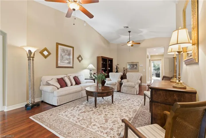 Living room with dark wood-style flooring, a ceiling fan, and high vaulted ceiling