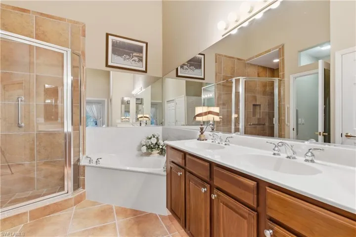Full bathroom with a garden tub, a stall shower, light tile patterned floors, and double vanity