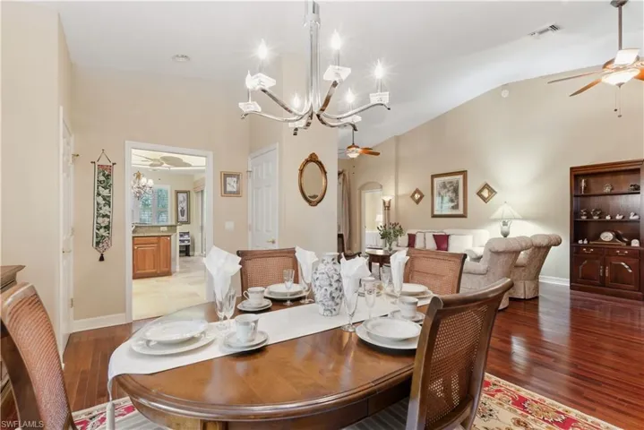 Dining space with a ceiling fan, a chandelier, wood finished floors, and vaulted ceiling