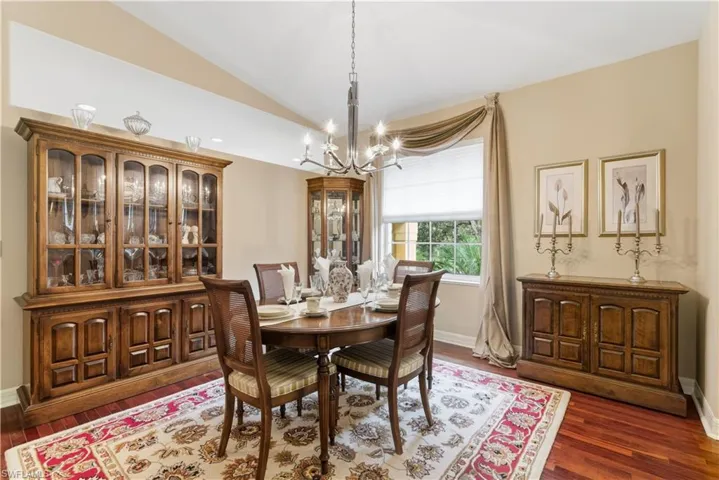 Dining space featuring a chandelier, dark wood-style flooring, vaulted ceiling, and recessed lighting