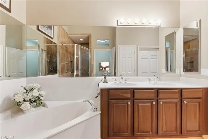 Full bath with a shower stall, double vanity, and a bath