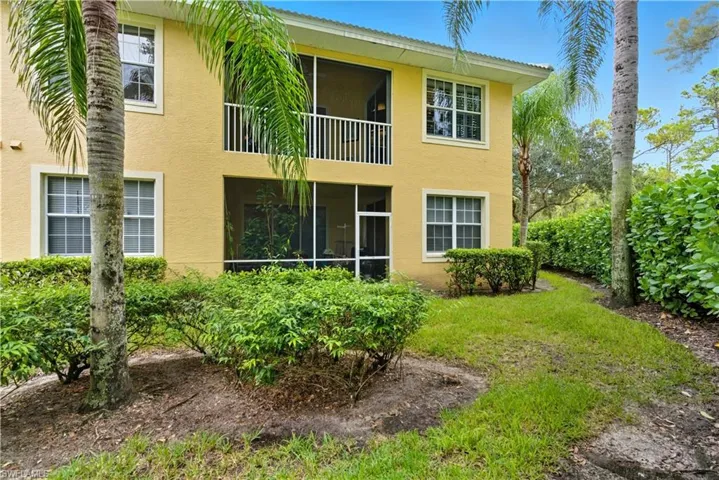 Back of property featuring a sunroom, a balcony, stucco siding, and a lawn