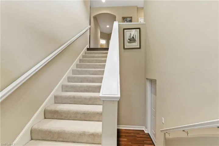 Stairs featuring wood finished floors, recessed lighting, and arched walkways