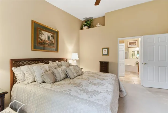 Bedroom featuring ceiling fan, ensuite bathroom, light carpet, and light tile patterned floors