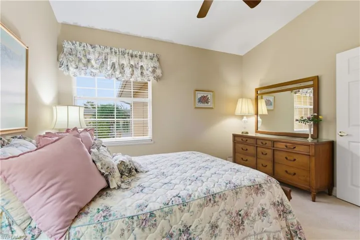 Bedroom featuring light colored carpet, ceiling fan, and vaulted ceiling