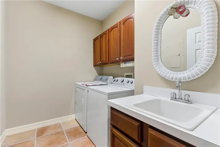 Laundry area featuring cabinet space, washing machine and clothes dryer, and light tile patterned floors