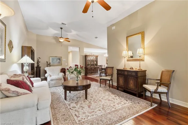 Living room with dark wood-type flooring, vaulted ceiling, and ceiling fan