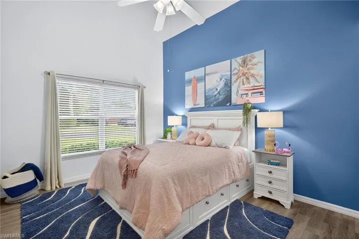 Bedroom featuring dark wood-style floors, ceiling fan, and a high ceiling