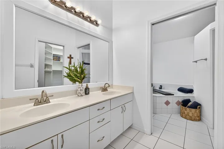 Bathroom featuring double vanity, a bath, light tile patterned flooring, and a walk in closet