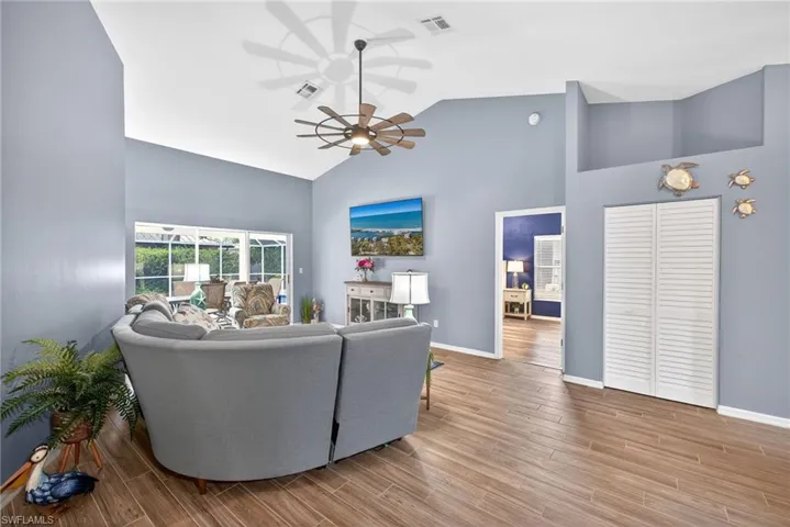 Living room featuring ceiling fan, wood tiled floors, and vaulted ceiling