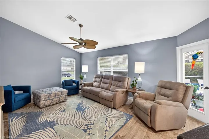 Living room with lofted ceiling, light wood-type flooring, and a ceiling fan