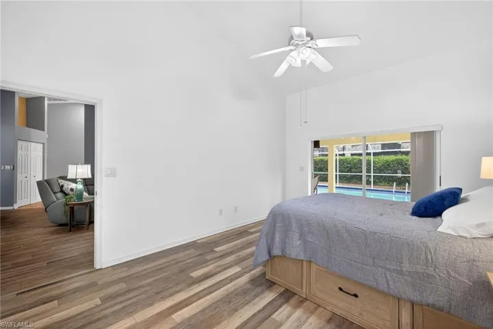Bedroom with dark wood finished floors, access to exterior, lofted ceiling, and ceiling fan