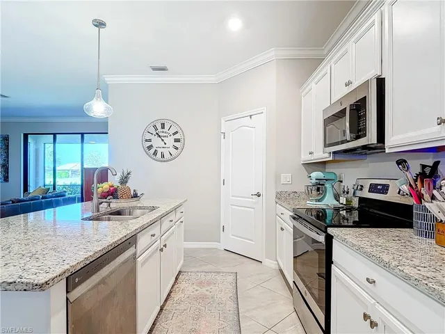 Kitchen featuring white cabinetry, appliances with stainless steel finishes, sink, and a center island with sink