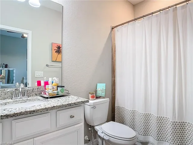 Bathroom featuring walk in shower, vanity, and toilet