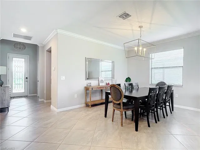 Tiled dining area with an inviting chandelier and crown molding