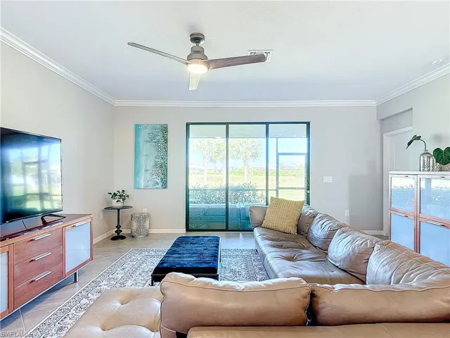 Tiled living room with ceiling fan and ornamental molding