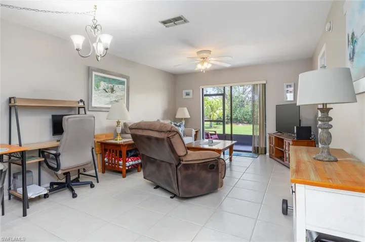 Tiled living room with ceiling fan with notable chandelier