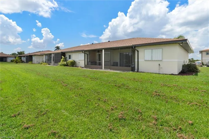 Rear view of house with a lawn and a sunroom