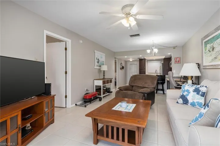 Tiled living room with ceiling fan with notable chandelier