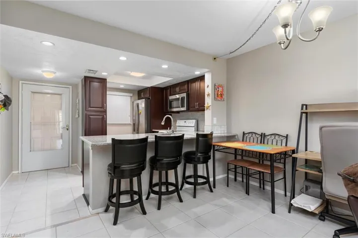 Kitchen featuring light tile patterned flooring, stainless steel appliances, kitchen peninsula, and decorative backsplash