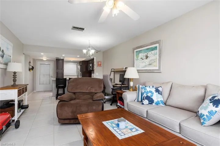 Living room featuring light tile patterned floors and ceiling fan with notable chandelier