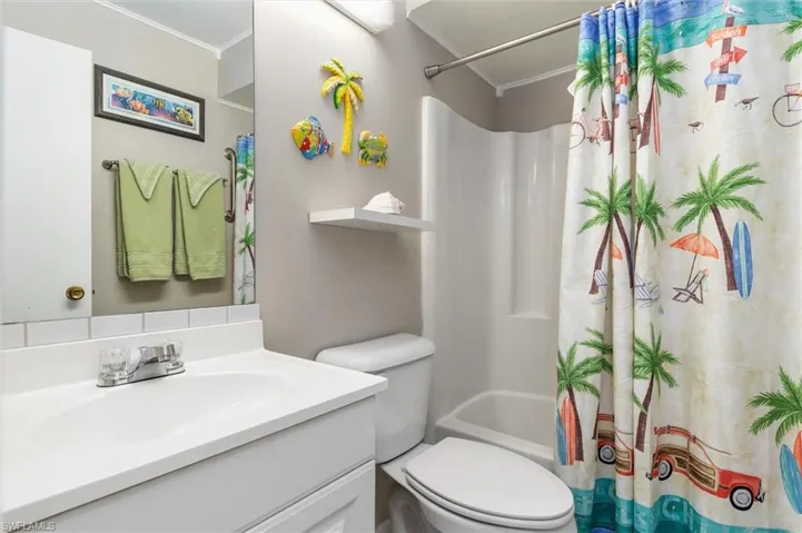 Full bathroom featuring crown molding, decorative backsplash, toilet, shower / tub combo with curtain, and vanity