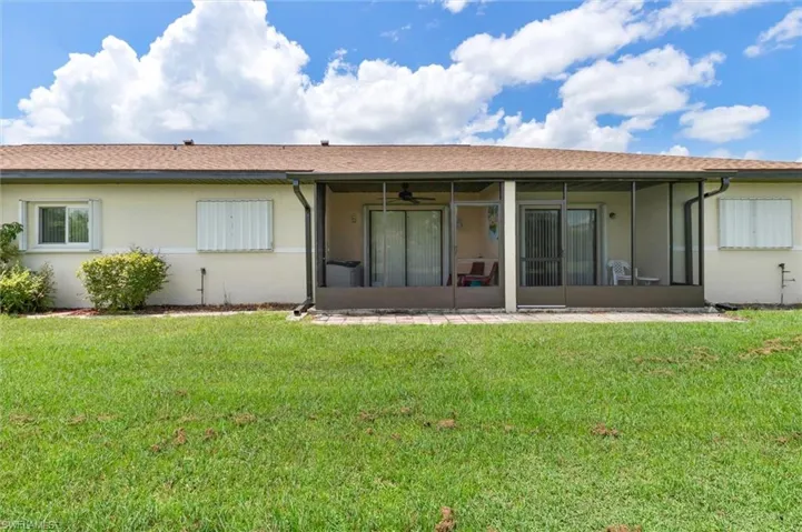 Rear view of property with a sunroom and a yard
