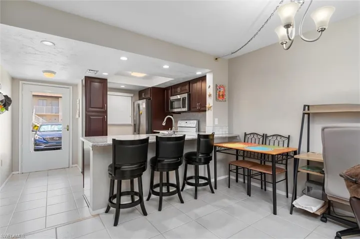 Kitchen featuring tasteful backsplash, stainless steel appliances, kitchen peninsula, and light tile patterned floors