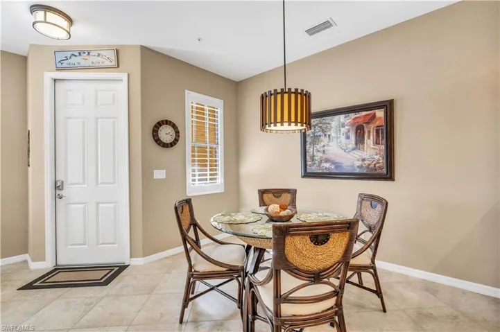 Neutral tile flooring, multi-pane window with louvered shutters, cylindrical pendant light fixture, flush-mount ceiling light, and six-panel interior door