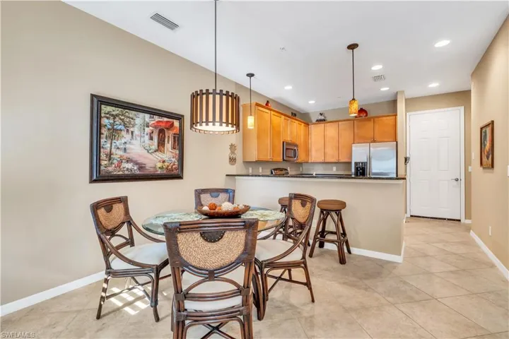 Kitchen featuring wooden cabinetry, dark countertops, a breakfast bar, recessed lighting, and tile flooring