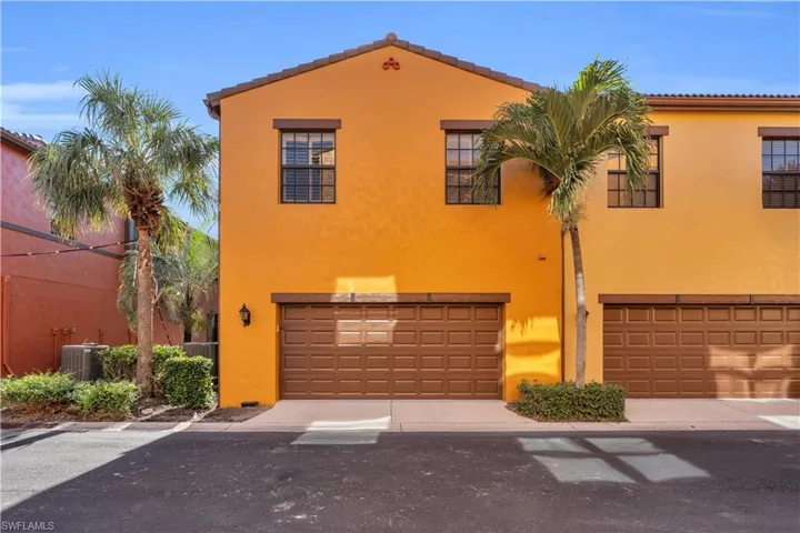 Two-story stucco exterior with multi-pane windows, dual-car garage doors, and integrated wall-mounted lighting