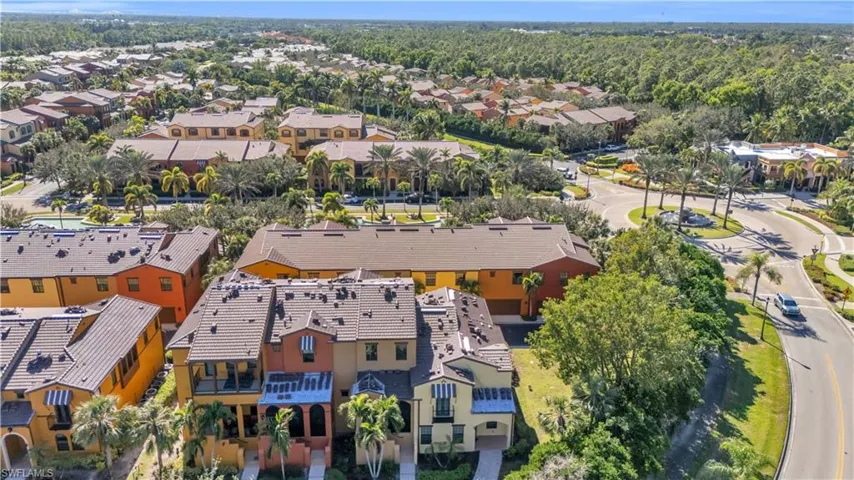 Aerial perspective of a multi-story residential building featuring a tile roof, stucco exterior, integrated balconies, and established landscaping