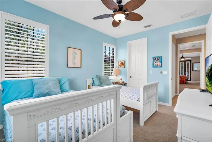 Interior space featuring neutral carpeting, plantation shutters, a ceiling fan with integrated lighting, and a six-panel door