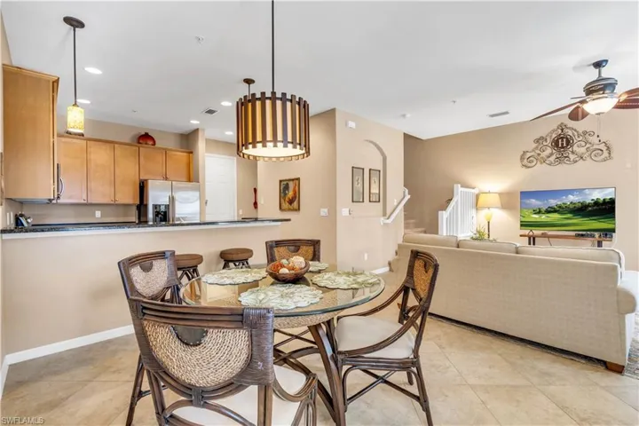 Kitchen featuring wood cabinetry, stone countertops, and a breakfast bar, complemented by recessed lighting and a decorative hanging pendant fixture
