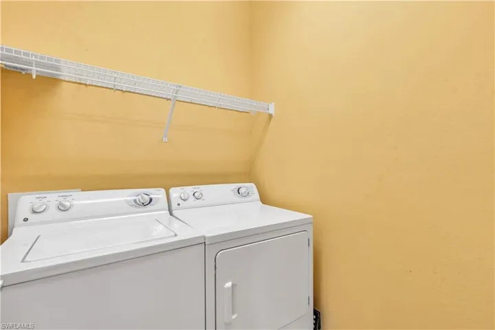 Laundry area featuring white appliance hookups and a mounted wire shelving unit