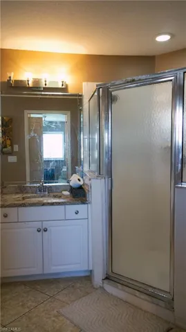 Bathroom with a shower with door, tasteful backsplash, and large vanity