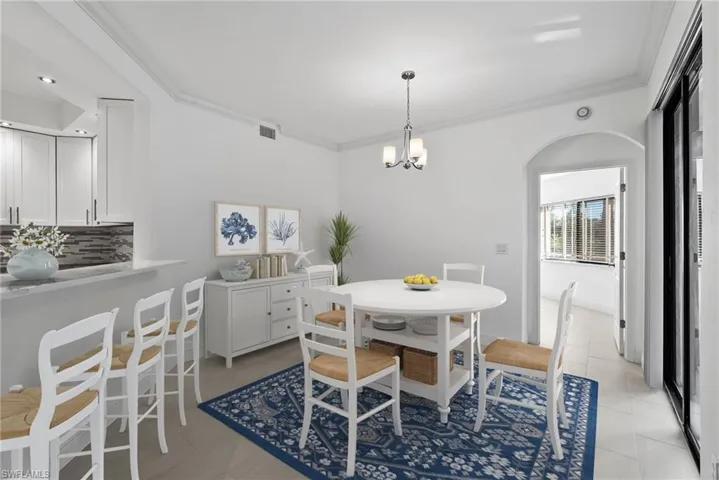 Tiled dining space with crown molding and a chandelier