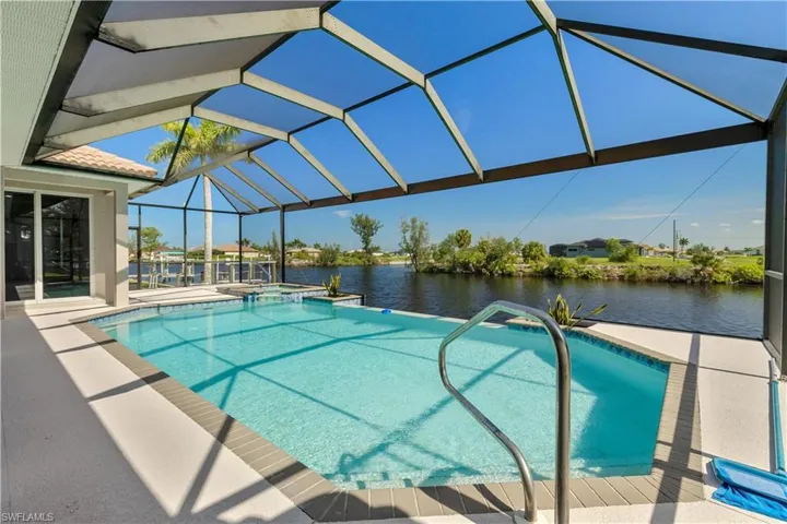 View of pool featuring a water view, glass enclosure, and a patio area
